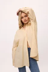 Camisa oversize a rayas verticales color amarillo y blanco, con cuello camisero, manga larga y cierre frontal con botones.