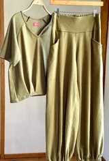 Conjunto color verde oliva, compuesto por un pantalón babucha con puño elastizado, bolsillos laterales y faja ancha elastizada en la espalda, y una remera de mangas cortas con escote en V.