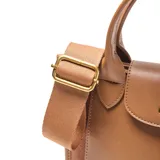 Cartera tipo tote bag de material símil cuero color habano, con cuerpo principal de tela texturada en tono similar. Posee doble asa corta, correa larga desmontable y regulable, cierre superior metálico y bolsillo interno con cierre. Presenta un bolsillo frontal con solapa de cuero y herrajes dorados.