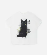 Remera de algodón color crudo, de corte holgado y mangas cortas. Estampado frontal con un gato negro y detalles gráficos en verde y negro.