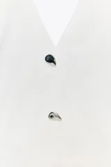Minivestido negro con forma de chaleco, cuello halter, escote en pico, botones metálicos y bajo globo.