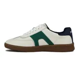 Zapatilla deportiva de hombre, estilo retro, color blanco con detalles en verde esmeralda en el lateral con borde festoneado. Posee cordones blancos y suela de goma marrón. El talón es de color azul marino.