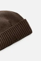Gorro de lana tejido en punto morado oscuro, con vuelta y detalles rotos.