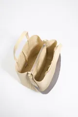 Bolso tote negro de cuero vacuno con doble asa corta y correa de tela extraíble. Interior con tres compartimentos y bolsillo con cremallera. Logo metálico de la marca en el frente.