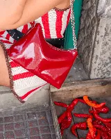 Cartera tipo baguette de cuero color rojo brillante, con correa de cadena plateada.