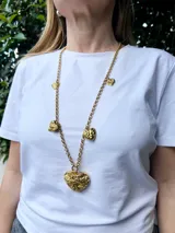 Collar largo dorado con cadena de eslabones y dijes de corazones texturizados.