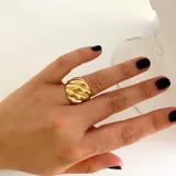 Anillo dorado con diseño texturizado en forma de croissant, fabricado en acero quirúrgico hipoalergénico con baño de oro de 18K.