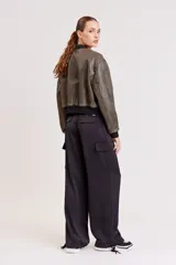 Pantalón de vestir color verde oliva, de corte ancho y tiro alto, con bolsillos laterales tipo cargo y detalle de pinzas en la cintura.