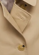 Trench coat azul marino con doble botonadura, cinturón ajustable, cuello de solapa, trabillas en los puños y abertura posterior en el bajo.