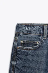 Pantalón de jean negro de corte recto, tiro alto y largo tobillero.