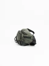 Riñonera verde militar con múltiples bolsillos con cierre, correa ajustable con hebilla y logo de la marca en el frente.