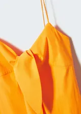 Vestido corto color amarillo, con tirantes finos, escote con nudo y cierre lateral con cremallera.