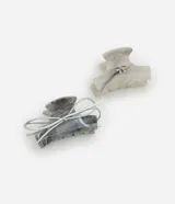 Set de dos pinzas para el pelo con diseño marmolado en tonos grises y blanco, adornadas con un lazo plateado. Una pinza tiene forma rectangular y la otra tiene forma irregular.