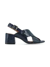 Sandalias negras de charol con tiras cruzadas, tacón cuadrado y pulsera al tobillo con hebilla metálica.