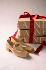 Zapatos de charol color beige con taco bloque de madera y tira sobre el empeine con hebilla dorada.