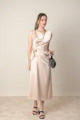 Vestido italiano color champagne, de corte recto, largo midi, sin mangas y con lazo lateral.