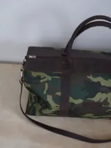 Bolso de lona color negro con detalles en cuero color tostado. Tiene doble asa de mano y correa de hombro ajustable y extraíble.