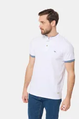 Remera de manga corta color azul grisáceo con cuello mao y tapeta de botones. Los puños de las mangas y el cuello son de color azul marino contrastante. Presenta un pequeño logo bordado en el pecho.