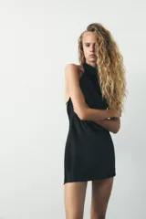 Vestido corto color verde esmeralda de satén con cuello halter y espalda descubierta con lazada.