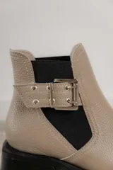 Botines Chelsea color beige con elásticos laterales negros, punta cuadrada, detalle de hebilla lateral y tacón bloque bajo.