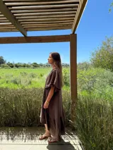 Vestido largo color beige, de corte amplio, con mangas cortas abullonadas y volado en el ruedo.