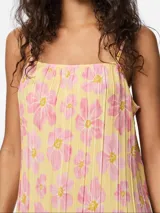 Vestido largo sin mangas, con escote cuadrado y tirantes finos. El tejido presenta un plisado vertical y un estampado repetido de flores grandes en tonos rosa sobre fondo amarillo claro.