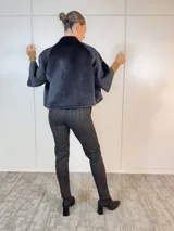 Chaqueta corta negra de terciopelo con cuello alto, manga corta y cierre frontal con botones grandes.