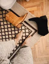 Bota corta de gamuza negra con bordados en hilo negro en la caña y puntera. Taco cuadrado y bajo.