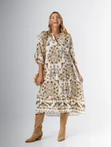Vestido midi de algodón italiano, color blanco con estampado boho chic en tonos naranja, marrón y verde. Tiene corte oversized, mangas 3/4 con volados y cinturón de soga trenzada con hebilla circular.