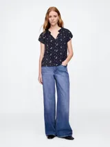 Blusa blanca de manga corta con escote en V y detalle de volados en el cuello.