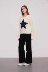 Sweater tejido de color rosa claro con una estrella roja grande en el centro.