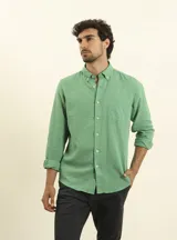Camisa azul marino de lino y algodón, con cuello abotonado, manga larga con puños enrollados, bolsillo de parche en el pecho y cierre frontal con botones.
