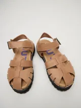 Sandalias romanas de cuero color tostado, con suela de goma y hebilla metálica lateral.