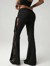 Pantalón acampanado negro con cintura alta drapeada y paneles de encaje floral en los laterales.