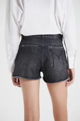 Short de jean negro con bolsillos delanteros diferenciados, tajo lateral, bota deshilachada, lavado stone wash y bigotes.