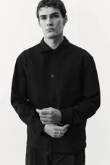 Sobrecamisa negra de manga larga con cuello inglés, tapeta lisa, canesú en la espalda y bolsillo superior de parche.