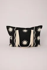 Bolso tote negro con estampado de estrellas blancas y asas de tela color crema.