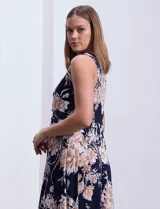Vestido maxi de seda fría con estampado floral en tonos beige y azul marino, de la marca Sandra Darren. Tiene cuello alto entrelazado con abertura ojal y aplique metálico.