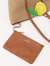 Bolso tote de hilo color beige con estructura firme y diseño espacioso. Tiene correas largas de cuero vacuno color marrón para llevar al hombro, aplique frontal de limón y logo metálico JCH.