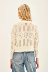 Cardigan color crema tejido en punto desagujado con volados tejidos en rib, calce crop y silueta ancha.