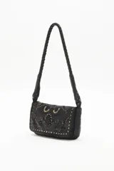 Cartera bandolera de cuero vacuno color negro, con correa trenzada y solapa con diseño calado y tachas. Incluye pañuelo estampado atado al asa.