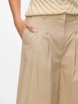 Pantalón oversize de pierna ancha color beige, con pliegues y bolsillos laterales.