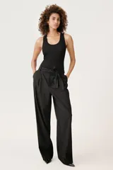 Pantalón negro de tiro alto con trabillas, bolsillos laterales y falsos bolsillos de vivo en la espalda. Incluye cinturón lazada en el mismo tejido.
