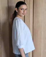 Blusa blanca de mangas 3/4 abullonadas con escote en V.