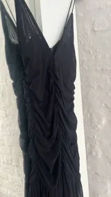Vestido corto negro de microtul con escote en V y breteles finos.
