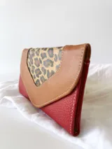 Billetera de cuero color rojo con solapa de cuero color marrón y aplique de cuero con estampado animal print.