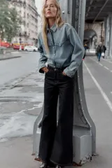 Jeans de denim oscuro, tiro alto, corte pierna ancha (wide leg) y cinco bolsillos. Presenta costuras contrastantes en color claro.