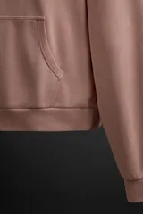 Sudadera con capucha color rosa viejo, confeccionada en tejido de algodón. Tiene cuello con capucha ajustable, manga larga, bolsillo tipo canguro y logo bordado en el pecho.