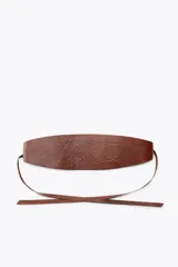 Cinturón tipo fajín de cuero color marrón con detalle de flores labradas. Cierre ajustable con lazada en el mismo material.