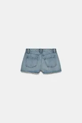 Shorts de jean de algodón, tiro alto, color azul claro desgastado. Presenta cinco bolsillos, cierre frontal con botón metálico y bajo desflecado con vuelta.